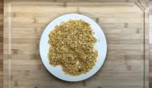 Crunchy cornflakes on a white plate set on a wooden board, perfect for breakfast or snack.